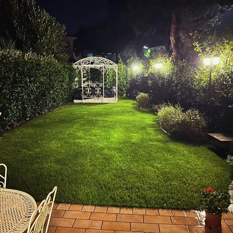 Giardino con prato, piante e gazebo illuminato la sera